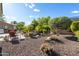 Landscaped backyard featuring mature trees, flowering bushes, and an outdoor seating area for relaxing and entertaining at 12780 W Desert Vista Trl, Peoria, AZ 85383