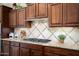 Close up of a well-appointed kitchen featuring a tiled backsplash, granite countertops, and dark wood cabinets at 12780 W Desert Vista Trl, Peoria, AZ 85383