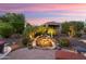 Backyard featuring a stone waterfall feature with lighting, surrounded by lush tropical landscaping at 12780 W Desert Vista Trl, Peoria, AZ 85383