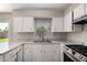 Well-lit kitchen features granite counters, stainless steel sink, and modern faucet at 1617 W Vineyard Rd, Phoenix, AZ 85041