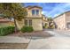 Two-story home with a stucco exterior, landscaping, and a tree in the front yard on a sunny day at 17374 W Adams St, Goodyear, AZ 85338