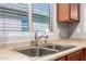 The kitchen sink area features stainless steel double sinks, light-colored countertops and wood cabinets at 18008 W Tina Ln, Surprise, AZ 85387