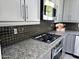 Modern kitchen with stainless steel gas range and microwave, granite counters, and dark tile backsplash at 3330 W Gran Paradiso Dr, Phoenix, AZ 85086