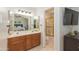 Bright bathroom featuring double sinks, wooden cabinets, vanity lighting, shower and a large TV at 3544 E Fox St, Mesa, AZ 85213