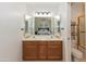 Bright bathroom featuring double sinks, wooden cabinets, vanity lighting, and a large mirror reflecting the bedroom at 3544 E Fox St, Mesa, AZ 85213