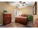 Cozy bedroom with a ceiling fan, wood floors, shuttered windows, and a decorative dresser at 3797 N 156Th N Dr, Goodyear, AZ 85395