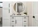 Contemporary bathroom with round mirror, white cabinets, and modern black and gold hardware at 39847 N 105Th Pl, Scottsdale, AZ 85262