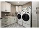 Functional laundry room with modern appliances, ample cabinet storage, and decorative patterned flooring at 39847 N 105Th Pl, Scottsdale, AZ 85262