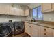 Bright laundry room with modern washer and dryer, storage cabinets and sink at 41590 N 108Th St, Scottsdale, AZ 85262