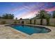 Backyard swimming pool featuring travertine tile, privacy wall, and lush landscaping under a vivid sunset sky at 5225 E Hearn Rd, Scottsdale, AZ 85254