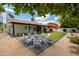 Landscaped backyard with lawn, gravel, and a fire pit surrounded by white chairs for outdoor enjoyment at 5402 E Michelle Dr, Scottsdale, AZ 85254