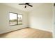 Bedroom features light wood floors, ceiling fan, and window views of the neighborhood at 5402 E Michelle Dr, Scottsdale, AZ 85254
