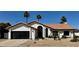 Charming single-story home with a desert landscape, black garage door and a terracotta tile roof at 5402 E Michelle Dr, Scottsdale, AZ 85254