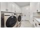 Well-lit laundry room with white cabinets, granite countertops, stainless steel washer and dryer, and tile flooring at 5901 E Sierra Morena St, Mesa, AZ 85215