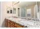 Double vanity bathroom with granite countertops, wood cabinetry and shower with glass door at 7002 E Exmoor Dr, Mesa, AZ 85208