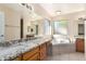 Bright bathroom with dual sinks, granite countertops, a soaking tub, and tile floors at 7002 E Exmoor Dr, Mesa, AZ 85208
