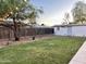 Spacious backyard featuring lush lawn, mature trees, and charming string lights, creating a serene outdoor oasis at 7943 W Mariposa Dr, Phoenix, AZ 85033