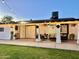 The covered patio features a ceiling fan, patio furniture and hanging plants at 7943 W Mariposa Dr, Phoenix, AZ 85033