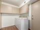 A bright laundry room features a side-by-side washer and dryer with upper cabinets and a neutral color scheme at 8306 E Via De Dorado --, Scottsdale, AZ 85258