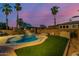 Backyard pool featuring palm trees and rock features with artificial grass at 1011 E Amberwood Dr, Phoenix, AZ 85048