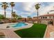 Backyard with a sparkling pool featuring a waterfall, surrounded by tropical palm trees and low-maintenance artificial turf at 1011 E Amberwood Dr, Phoenix, AZ 85048