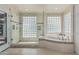Large bathroom with glass block window accents, a jacuzzi tub, a glass walk-in shower, and tiled flooring at 10205 E Corrine Dr, Scottsdale, AZ 85260