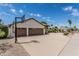 View of the home's three-car garage with basketball hoop and expansive driveway and desert landscaping at 10205 E Corrine Dr, Scottsdale, AZ 85260