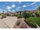 An exterior view of the house showcasing the desert landscaping, circular drive, and tile roof at 10205 E Corrine Dr, Scottsdale, AZ 85260
