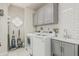 Bright laundry room with white subway tiles, gray cabinetry, and modern washer and dryer at 10205 E Corrine Dr, Scottsdale, AZ 85260