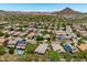 An aerial view of a desert community featuring lush landscaping, homes, mountains, and solar panels on roofs at 12727 W Lowden Rd, Peoria, AZ 85383