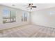 Bright bedroom with neutral carpet, ceiling fan, and multiple windows offering views of the surrounding landscape at 12727 W Lowden Rd, Peoria, AZ 85383