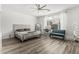 Bright bedroom featuring wood-look floors, a ceiling fan, and a cozy seating area by the window at 13750 W Roanoke Ave, Goodyear, AZ 85395
