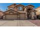 Front of a two-story home featuring a three-car garage, neutral color scheme, desert landscaping, and a concrete driveway at 13750 W Roanoke Ave, Goodyear, AZ 85395