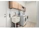 Functional laundry room featuring a utility sink, modern washer and dryer, and upper cabinets for storage at 13750 W Roanoke Ave, Goodyear, AZ 85395