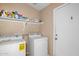Bright laundry room features washer, dryer, shelving, and convenient access door at 16240 W Maricopa St, Goodyear, AZ 85338