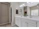 Bathroom featuring dual sinks, white cabinetry, modern fixtures, and wood-look tile flooring at 18023 W Statler St, Surprise, AZ 85388