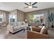 Bright and airy living room featuring a comfortable sofa, two leather chairs, and large windows, dining room in background at 18023 W Statler St, Surprise, AZ 85388