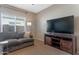 Comfortable living room with carpet, large TV, and window providing natural light at 18023 W Statler St, Surprise, AZ 85388