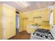 This kitchen features yellow cabinetry, a gas range, and tile countertops at 2308 W Marlette Ave, Phoenix, AZ 85015