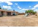 Large dirt backyard featuring a swing set, adjacent to the house with sliding door entry at 2308 W Marlette Ave, Phoenix, AZ 85015