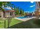 Well-manicured backyard featuring a pristine pool, lush green lawn, and charming string lights for evening ambiance at 45247 W Jack Rabbit Trl, Maricopa, AZ 85139
