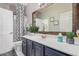 Bathroom featuring dark cabinets, a white countertop, decorative mirror, and a shower at 45247 W Jack Rabbit Trl, Maricopa, AZ 85139