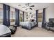 Bright bedroom featuring a large window, stylish curtains, ceiling fan, and a cozy bed at 45247 W Jack Rabbit Trl, Maricopa, AZ 85139