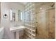 Updated bathroom with glass-block shower, pedestal sink, and travertine tile at 4744 E Foothill Dr, Paradise Valley, AZ 85253