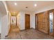 Long hallway with travertine flooring, recessed lighting, and custom wood doors at 4744 E Foothill Dr, Paradise Valley, AZ 85253