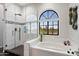 Elegant bathroom with a soaking tub, separate shower, and arched window at 8879 E Greenview Dr, Gold Canyon, AZ 85118
