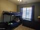 Spacious bedroom featuring a bunk bed, window with curtains, and dark wood dresser at 9137 W Coolbrook Ave, Peoria, AZ 85382