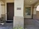 Cozy covered front porch featuring a sturdy front door, textured walls, and neighborhood views through the adjacent window at 9137 W Coolbrook Ave, Peoria, AZ 85382