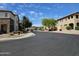 Street view of the community lined with sidewalks, lush trees and beautiful townhome-style homes under a clear blue sky at 9137 W Coolbrook Ave, Peoria, AZ 85382
