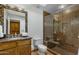 Bathroom with a tiled shower and seat, wooden cabinets, granite countertops, toilet, and decorative mirror at 9154 E Sunflower Ct, Scottsdale, AZ 85266